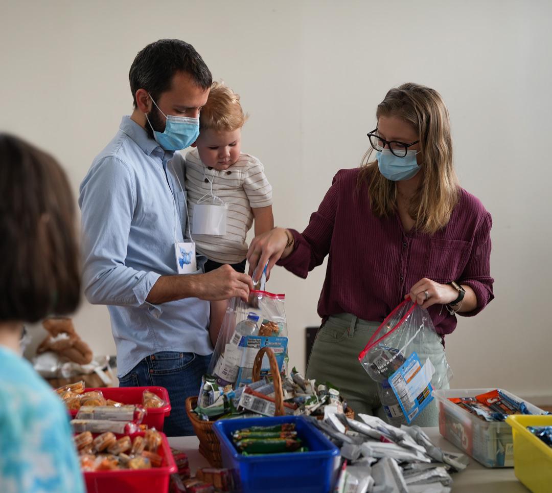 Family with child working on packing bags of food for the homeless